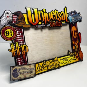 May include: A Harry Potter themed picture frame with a wood-toned frame and a variety of colorful accents. The frame features a Hogwarts Express Platform 9 3/4 sign, a Sorting Hat, a golden snitch, and a flying Ford Anglia. The frame also includes the text "Universal Studios" and "Dumbledore's Army".