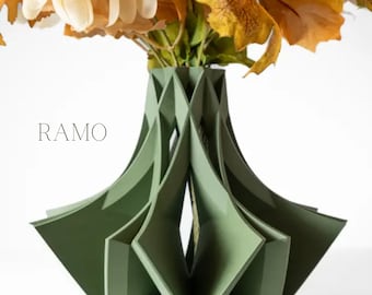 May include: A green geometric vase with a unique, folded design. The vase is filled with a bouquet of white and orange flowers.