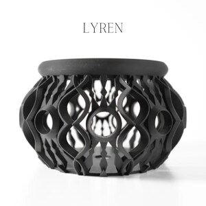 May include: A black decorative bowl with an open, geometric design. The bowl has a rounded shape with a thick rim and a series of interconnected, curved lines forming the body. The word "LYREN" is printed in black above the bowl.