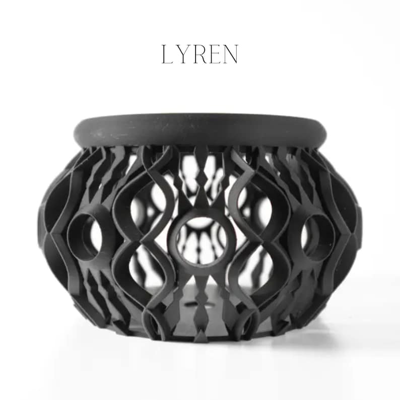 May include: A black decorative bowl with an open, geometric design. The bowl has a rounded shape with a thick rim and a series of interconnected, curved lines forming the body. The word "LYREN" is printed in black above the bowl.