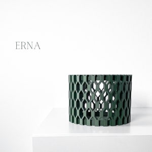 May include: A dark green cylindrical decorative object with a geometric honeycomb pattern. The object is displayed on a white surface against a white background. The word "ERNA" is printed in a minimalist font.