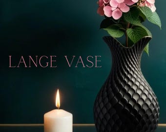 May include: A black decorative vase with a textured pattern, holding pink flowers. A white candle on a gold-colored plate is lit, with the text "LANGE VASE" in pink.