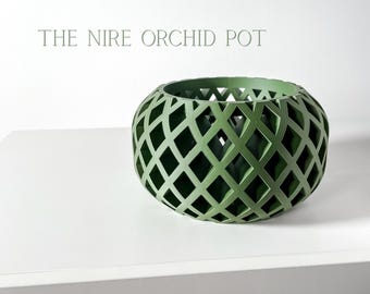 May include: A green, openwork orchid pot with a diamond pattern. The pot is round and sits on a white surface. The text "THE NIRE ORCHID POT" is above the pot.