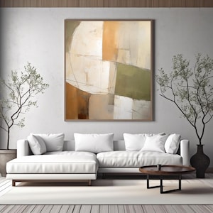 May include: Abstract art print in a wooden frame. The artwork features a geometric design with beige, olive green, and brown tones. A white sectional sofa, a round wooden coffee table, and decorative plants complete the living room setting.