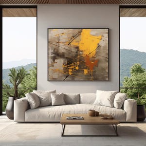 Puede incluir: Pintura abstracta con colores amarillo, marrón y gris. La pintura presenta un diseño geométrico con líneas y formas. La pintura está colgada en una pared de una sala de estar con un sofá blanco y una mesa de café.