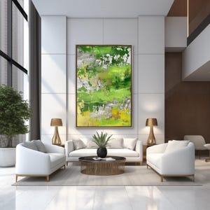 May include: Abstract painting with green, yellow, and silver paint on a white canvas. The painting is hanging on a white wall in a modern living room with white sofas and a coffee table.