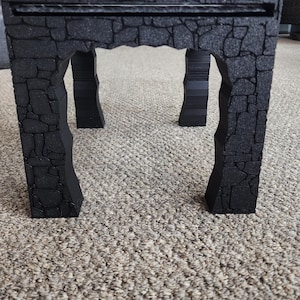 Może przedstawiać: Czarny kamienny łuk z szorstką, fakturowaną powierzchnią. Łuk jest wykonany z pianki i ma realistyczny wygląd kamienia.