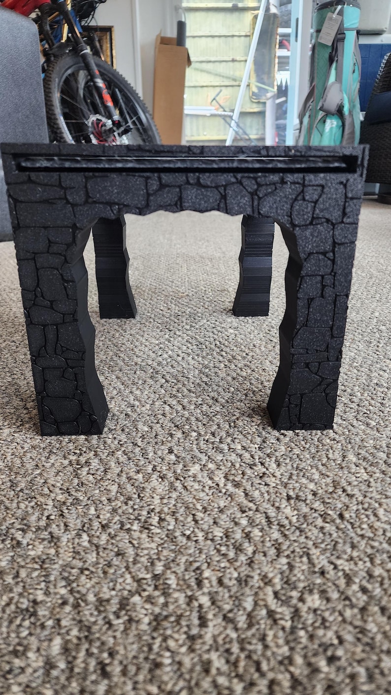 Może przedstawiać: Czarny kamienny łuk z szorstką, fakturowaną powierzchnią. Łuk jest wykonany z pianki i ma realistyczny wygląd kamienia.