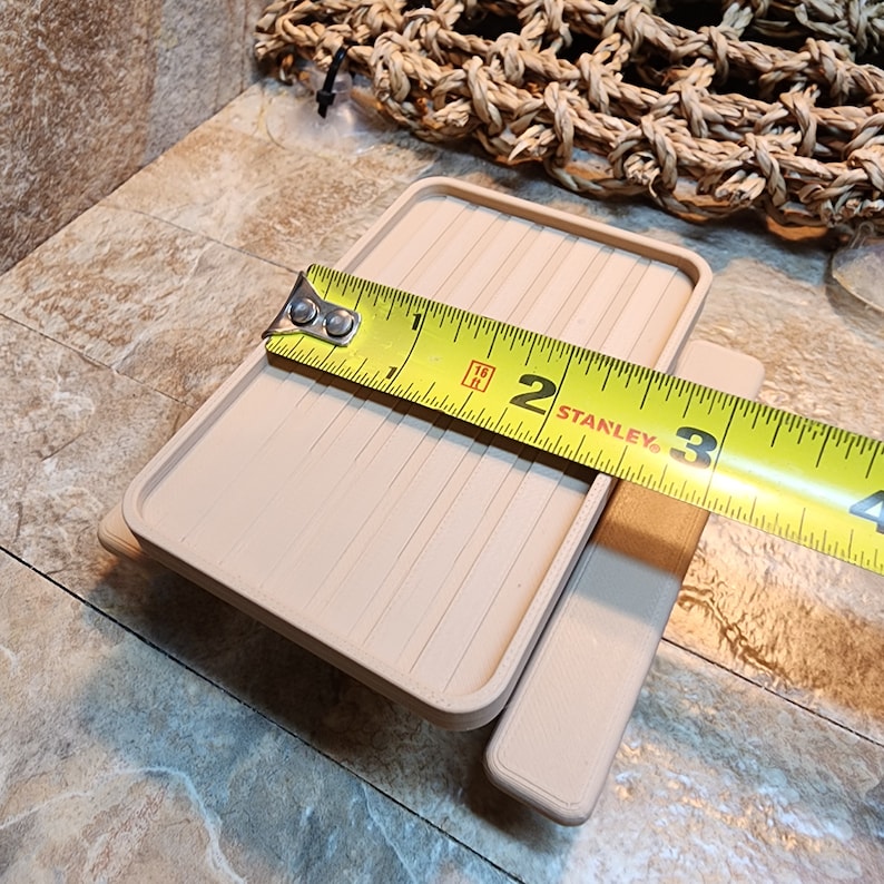 May include: A beige miniature table with a flat top and a bench seat. The table is being measured with a yellow tape measure that reads "2 STANLEY 3".