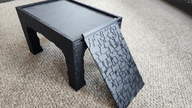 Może przedstawiać: Czarny drewniany st&oacute;ł z fakturowaną powierzchnią i czarna rampa z fakturowaną powierzchnią. St&oacute;ł i rampa są połączone.