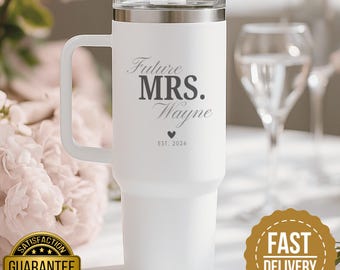 May include: White insulated tumbler with a handle and a silver rim. The tumbler features the text "Future MRS. Wayne" with a heart and "EST. 2026". The tumbler has a straw and a clear lid.