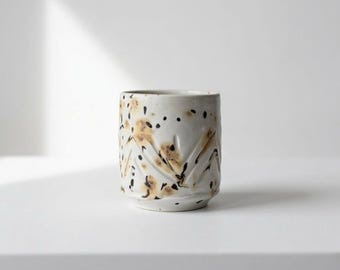 Tazza "Goccia" in ceramica artigianale (8x7 cm). Bianco puntinato con artistici schizzi ambra. Un pezzo unico fatto a mano per il tuo caffè.