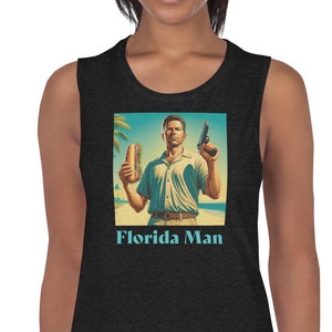May include: A black sleeveless shirt featuring a graphic of a man holding a sandwich and a gun. The text "Florida Man" is printed below the graphic.