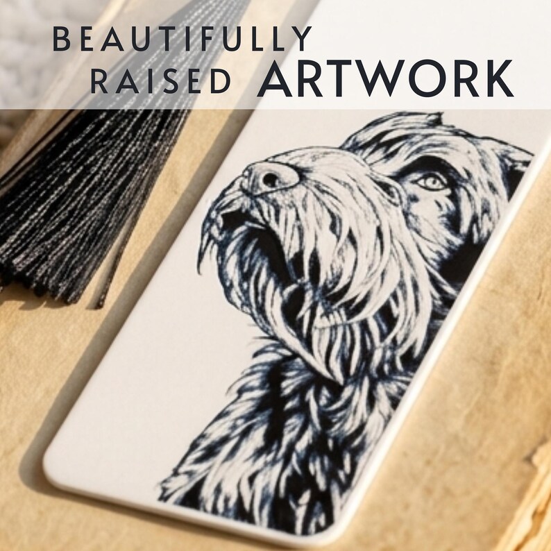 May include: A white rectangular bookmark featuring a black ink illustration of a terrier dog's head and a black tassel. The text BEAUTIFULLY RAISED ARTWORK is printed in black at the top. The bookmark has a smooth surface and rounded corners.