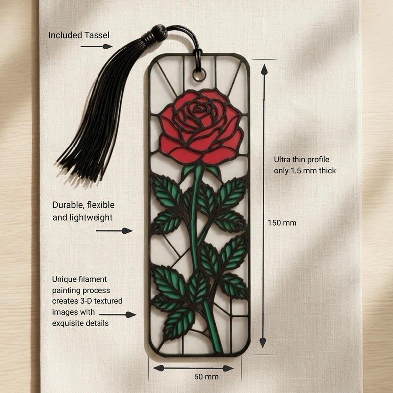 May include: A rectangular bookmark featuring a red rose with green leaves in a black frame, accompanied by a black tassel. The bookmark measures 150 mm by 50 mm with a 1.5 mm thickness. Text labels indicate it is durable, flexible, and lightweight.