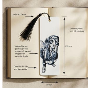 May include: A white rectangular bookmark featuring a black and white illustration of a dachshund. The bookmark includes a black tassel, measures 150 mm in length and 50 mm in width, and has an ultra thin profile of 1.5 mm thickness. The design is created with a filament painting process.