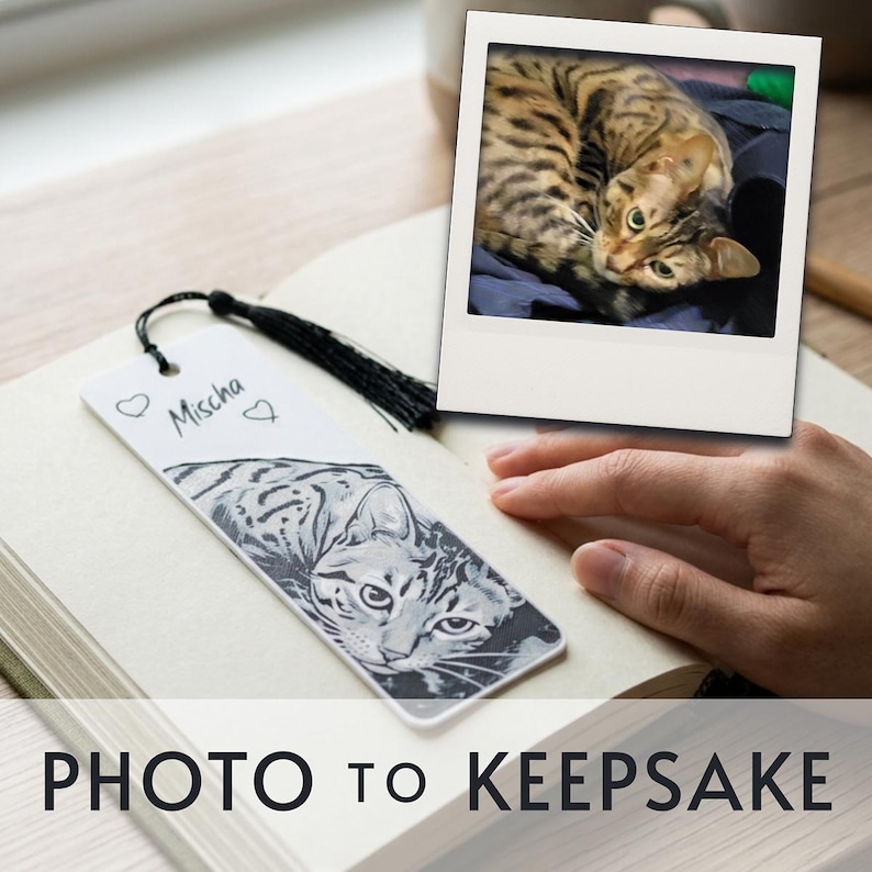 May include: A white rectangular bookmark featuring a black and white illustration of a tabby cat, the name Mischa written in cursive, two small heart outlines, and a black tassel attached to the top. A square photo of the same cat is included.