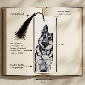 May include: A rectangular white bookmark featuring a black and white illustration of a German Shepherd dog. The bookmark includes a black tassel, measures 150 mm by 50 mm, and has a 1.5 mm thickness. The surface displays a textured 3-D appearance.