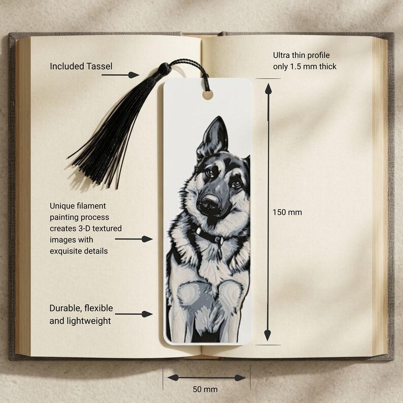 May include: A rectangular white bookmark featuring a black and white illustration of a German Shepherd dog. The bookmark includes a black tassel, measures 150 mm by 50 mm, and has a 1.5 mm thickness. The surface displays a textured 3-D appearance.