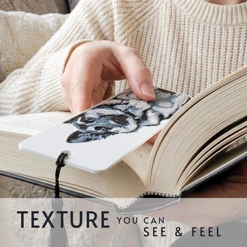 May include: A white rectangular bookmark featuring a detailed black and white illustration of a dog's face. The bookmark has a small hole at the bottom with a black string tassel attached. The text "TEXTURE YOU CAN SEE & FEEL" is printed below.