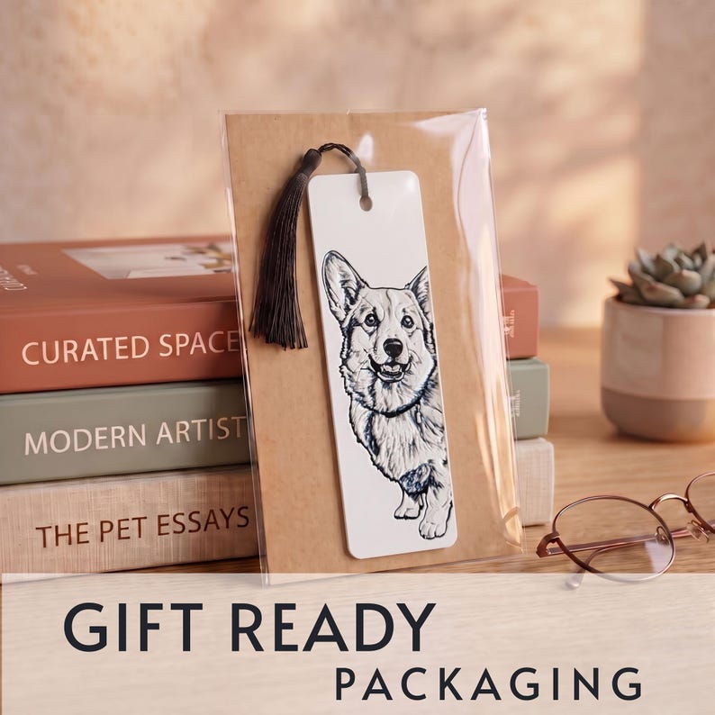 May include: A rectangular white bookmark featuring a detailed black and white ink illustration of a Corgi dog. The bookmark has a hole at the top with a dark brown tassel attached and is enclosed in a clear plastic sleeve on a brown card backing.