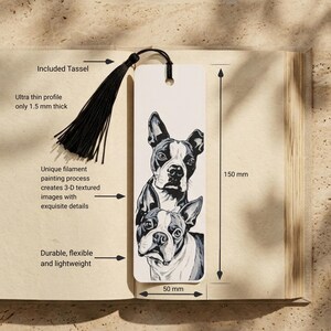 May include: A rectangular bookmark measuring 150 mm by 50 mm and 1.5 mm thick, featuring a black and white illustration of two Boston Terrier dogs. The bookmark includes a black tassel attached through a hole at the top center.
