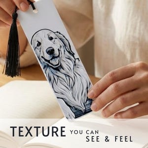 May include: A rectangular white bookmark featuring a detailed black and white illustration of a golden retriever dog. The bookmark includes a black tassel attached to the top with a silver metal eyelet. The text reads: TEXTURE YOU CAN SEE & FEEL.
