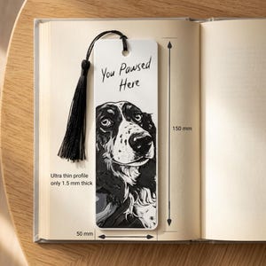 May include: A white rectangular bookmark featuring a black and white illustration of a dog and the text "You Pawsed Here". It includes a black tassel, measures 150 mm by 50 mm, and has an ultra thin profile of 1.5 mm thick.