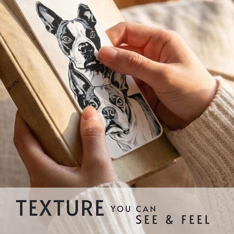 May include: A rectangular bookmark featuring a black and white ink illustration of two Boston Terrier dogs stacked vertically. The bookmark has a textured surface and is positioned against a book. The text reads: TEXTURE YOU CAN SEE & FEEL.