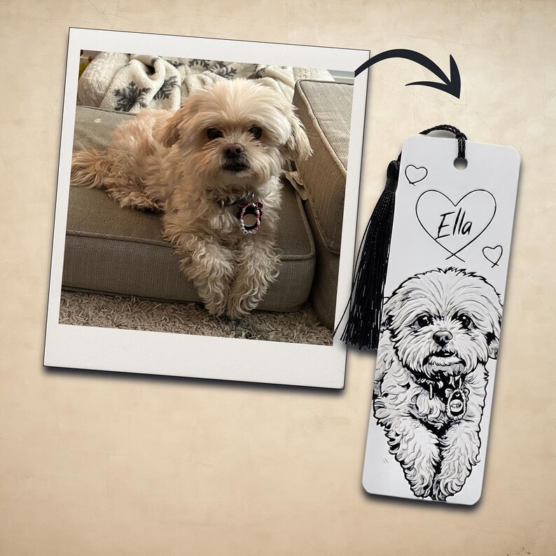 May include: A rectangular white bookmark featuring a black and white line art illustration of a fluffy dog with a collar. The name Ella is written inside a heart shape above the dog, and a black tassel is attached to the top of the bookmark.