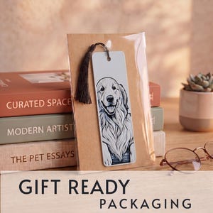 May include: A rectangular white bookmark featuring a detailed black and white line drawing of a golden retriever dog. The bookmark has a hole at the top with a dark brown tassel attached and is enclosed in a clear plastic sleeve on a brown card.