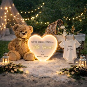 May include: A teddy bear, heart-shaped sign, and baby onesie are arranged outdoors. The sign reads "We've been keeping a Little Secret" and "Due August 2026." The onesie says "Baby Miller." Decorative lights and greenery surround the items.