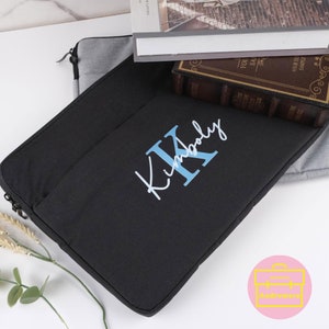 May include: Black laptop sleeve with a zipper closure and a blue embroidered monogram that says "Kimberly" with a large "K".
