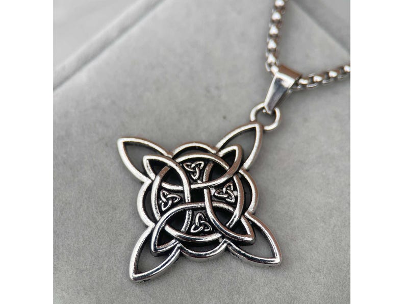 May include: Silver Celtic knot pendant necklace with a detailed intricate design. The pendant is attached to a silver chain.