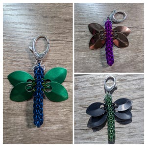 May include: Three dragonfly keychains. One has green wings and a blue body, another has copper wings and a purple body, and the third has black wings and a green body. Each keychain has a silver clasp.