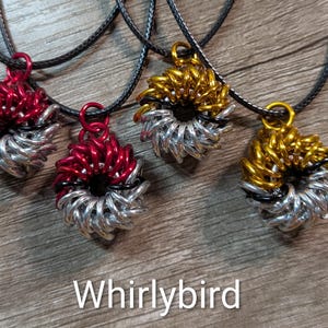 May include: Four handmade pendant necklaces with circular, woven designs. Two are red and silver, and two are gold and silver. The pendants are suspended from black cords. The word "Whirlybird" is displayed in white text at the bottom.