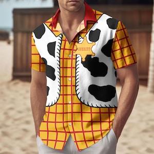 May include: A short-sleeved button-down shirt featuring a yellow plaid pattern with red accents. The shirt has a white vest design with black cow spots and a sheriff badge. The collar is red.