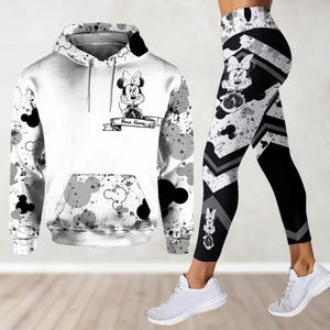 May include: A white hoodie with a black and white splatter paint design featuring Mickey Mouse silhouettes and a cartoon Minnie Mouse with the text "Your Name". Matching black and white leggings with a splatter paint design and Mickey Mouse silhouettes.