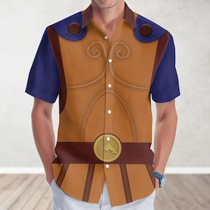 May include: A short-sleeved button-down shirt with a Hercules costume design. The shirt features a tan bodice with brown detailing and a gold belt buckle. The sleeves and shoulder accents are navy blue. A casual, patterned shirt.