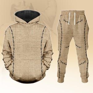 May include: A two-piece brown outfit comprising a hoodie and sweatpants. The hoodie features a black-lined hood and black stitching details. The sweatpants have a drawstring and matching black stitching. The outfit has a burlap sack appearance.