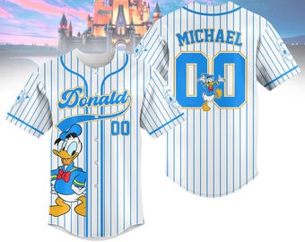 Può includere: Due maglie da baseball bianche con strisce blu. Una maglia ha "Donald" e un'anatra dei cartoni animati sul davanti e "00" sul petto. L'altra maglia ha "MICHAEL" e "00" sul retro.