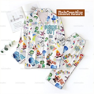 May include: White Inside Out pyjama set featuring characters and phrases from the film. The long-sleeved top and trousers are covered in colourful illustrations and text, with the words "INSIDE OUT" prominently displayed.