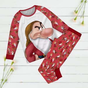 May include: Red and white pajamas with a grumpy dwarf character print. The top has a white background with a red raglan sleeve and the pants have a red background with a white dwarf print.