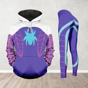 May include: A purple and white hooded sweatshirt and matching leggings set. The sweatshirt features a large teal spider emblem on the front, with web designs on the sleeves. The leggings are purple with teal and pink accents.