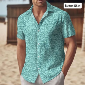 Pode incluir: Uma camisa azul clara com botões com um padrão repetido de personagens alienígenas de desenhos animados. A camisa tem mangas curtas e uma gola clássica. O texto "Button Shirt" está no canto superior direito.