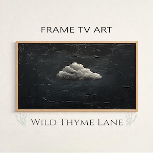 May include: A framed piece of art for a TV screen. The artwork features a textured, dark background with a fluffy, white cloud in the center. The frame is a light brown color. The text "FRAME TV ART" is above the artwork, and "WILD THYME LANE" is below.