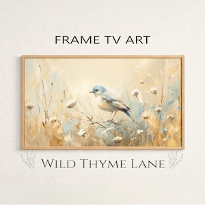 May include: A framed artwork featuring a watercolor painting of a blue bird perched on a branch amidst tall grass and wildflowers. The artwork has a light beige background and is framed in a light wood frame. The text "FRAME TV ART" and "WILD THYME LANE" are displayed.