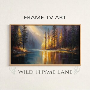May include: A framed landscape painting of a forest scene with a lake reflecting the trees and sunlight. The artwork uses blues, greens, and golds, with the text "FRAME TV ART" and "WILD THYME LANE".