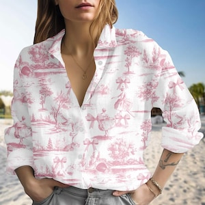 Könnte beinhalten: Weißes Hemd mit rosa Toile-de-Jouy-Muster mit Tänzern, Bäumen und Schleifen. Das langärmlige Hemd hat einen klassischen Kragen und ist aus leichtem Stoff gefertigt. Das Hemd ist am Ausschnitt aufgeknöpft.