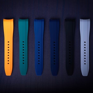 May include: A collection of seven watch straps in various colors, including yellow, orange, teal, blue, black, gray, and white. Each strap has a series of holes for adjustment and a curved design for the watch face.